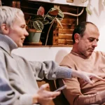 Kanepede oturan çift tablet ve akıllı telefon inceliyor Eşimi Araştırmak İstiyorum