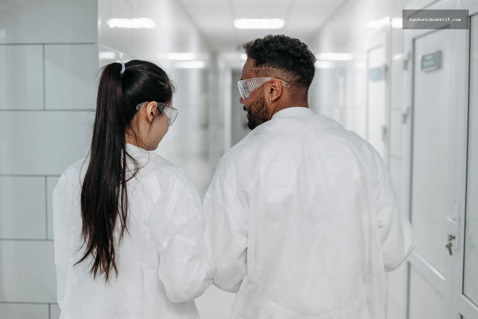 Laboratory scientists collaborating in safety gear examining data together during Eş Araştırma