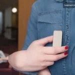 Smartphone ekranında otel rezervasyon uygulaması açılmış, modern kahve masasında otururken kullanıcıyı gösteren