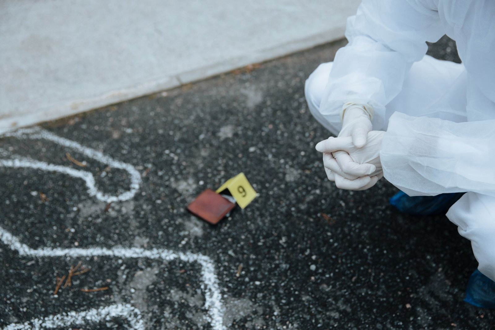 Forensic dedektif asfalttaki suç sahnesi çizgisini inceleyen giyimli çalışırken detaylı dedektif araştırması