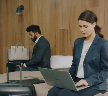Otel odasında dizüstü bilgisayarla konaklama kaydı bulma işlemi yapan profesyoneller