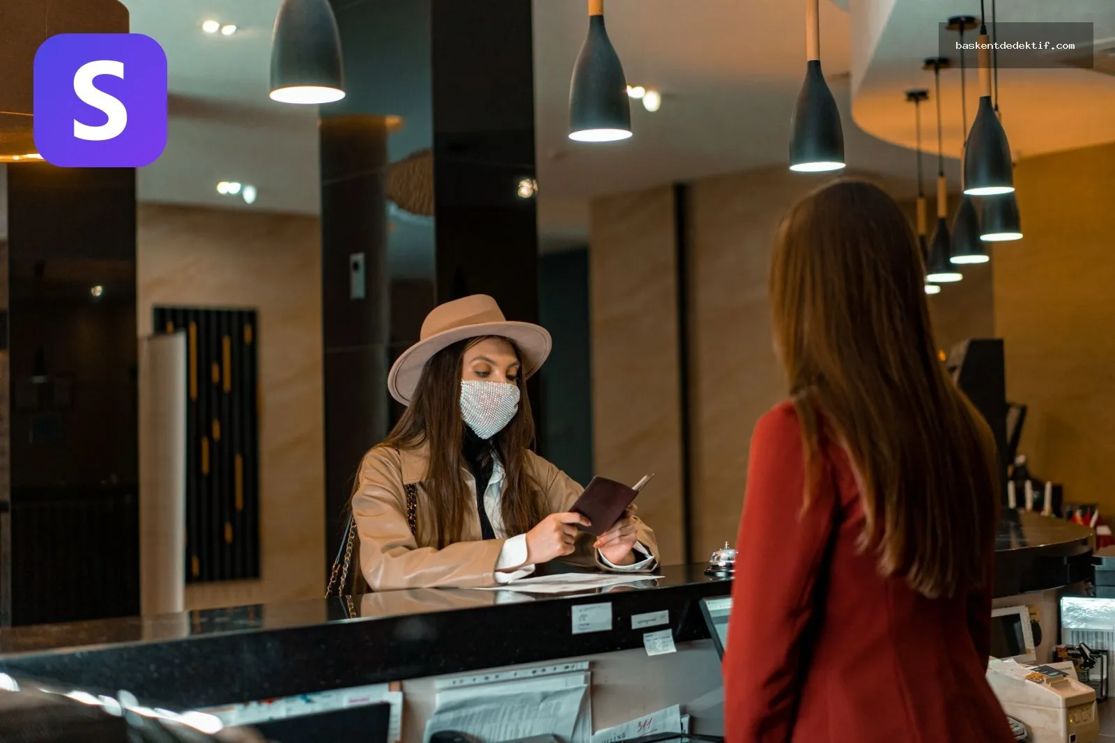 Otel Kayıtları Nasıl Çıkartılır Maske takan kadın otel kayıt masasında işlem yapıyor