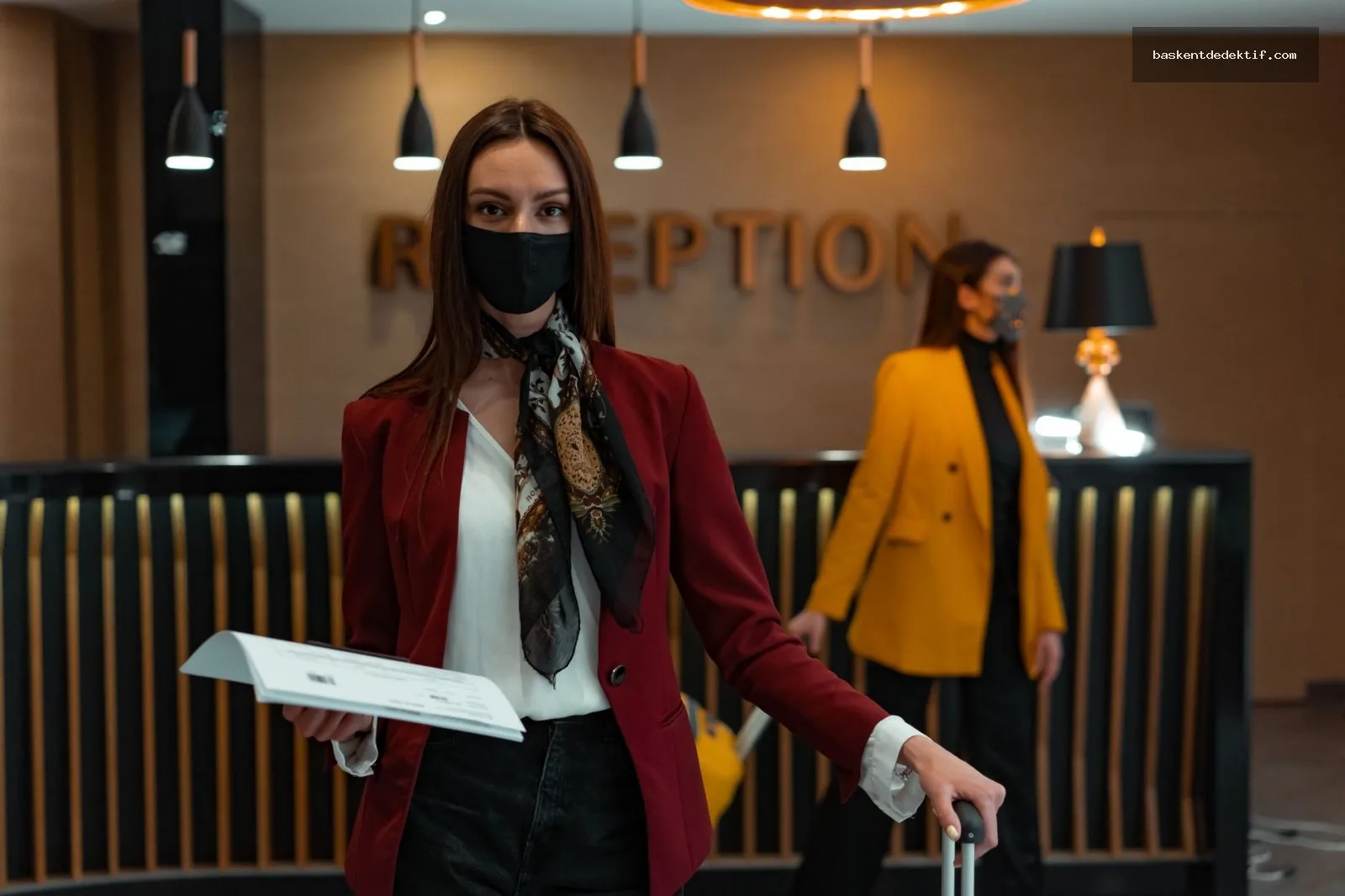 Resepsiyonda otel kaydı yaptıran müşteri ve maskeli görevli