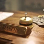 Retro resepsiyonda altın servis çanı ve otel kayıtları kitabı